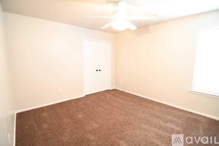 A room with a carpeted floor and a ceiling fan.