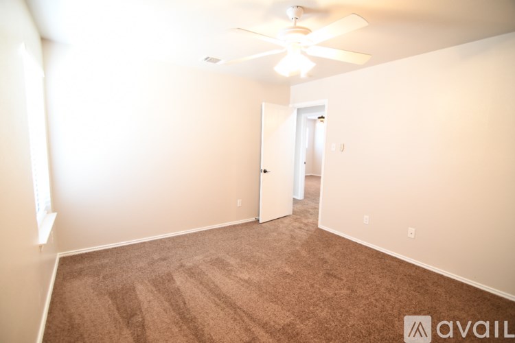 A room with a carpeted floor and a ceiling fan.