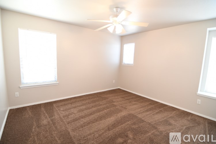 A room with a carpeted floor and a ceiling fan.