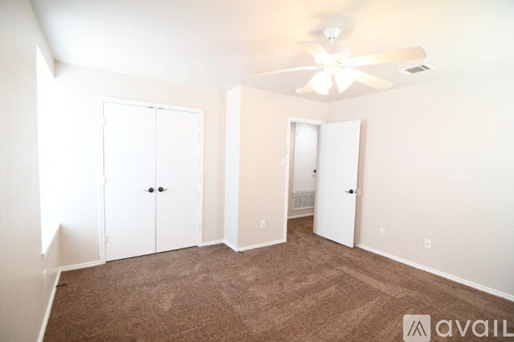 A room with a carpeted floor and a ceiling fan.