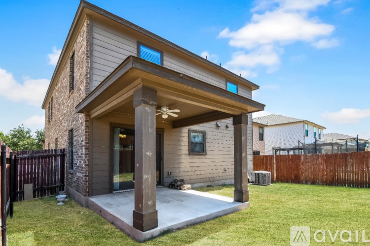 A room with a carpeted floor, a ceiling fan, and three windows.