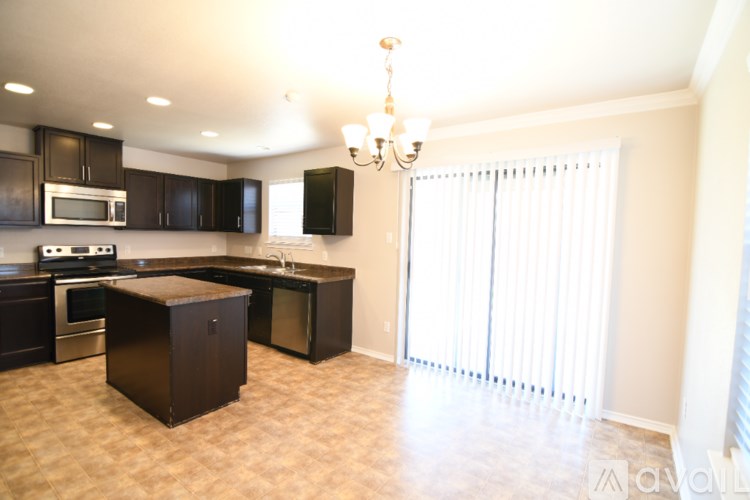 A kitchen with a brown island and black cabinets.