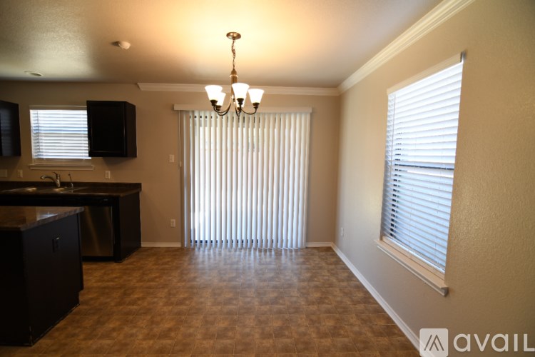 A room with a kitchen area and a window with blinds.