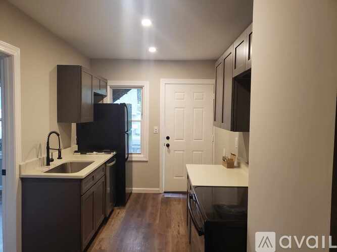 A kitchen with a black refrigerator and wooden floors.