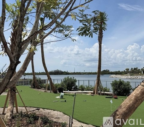 A golf course with a green putting mat and a tree in the foreground.