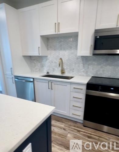 A kitchen with white cabinets and a black island.