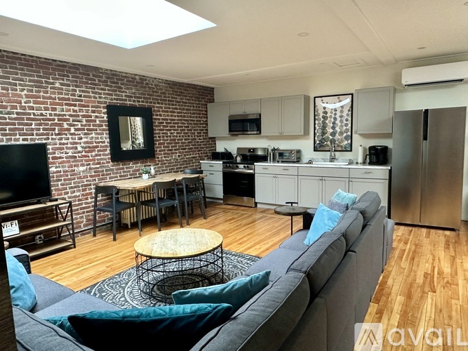 A living room with a grey couch and a brick wall.