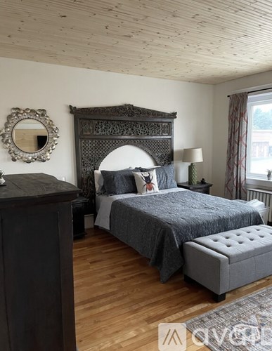 A bedroom with a large bed and a wooden dresser.