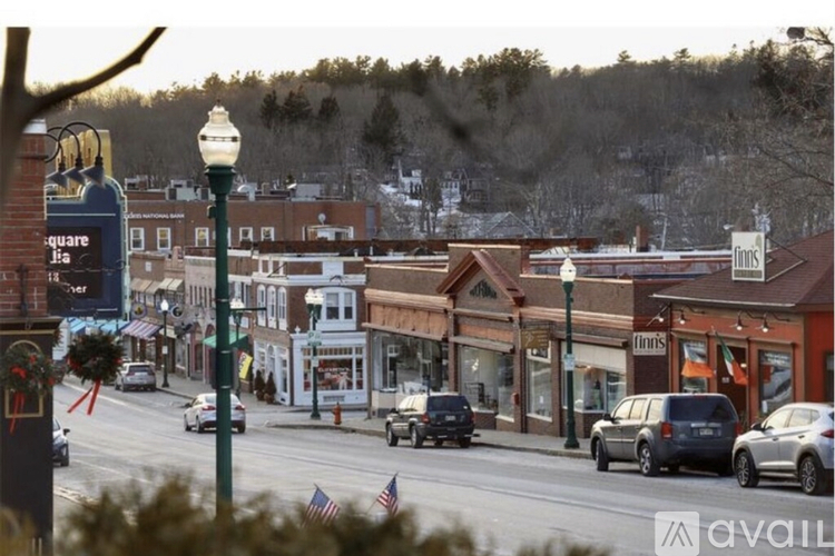 A street view of a small town with cars driving on the road and buildings on the side.