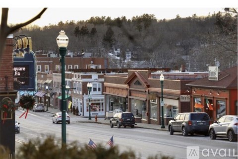 A street view of a small town with cars driving on the road and buildings on the side.