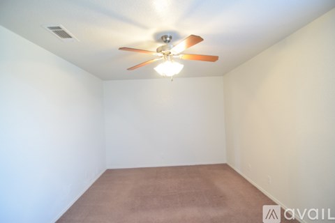 Empty room with a ceiling fan and carpeted floor.