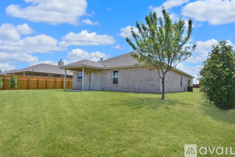 A house with a fence and a tree in front of it.