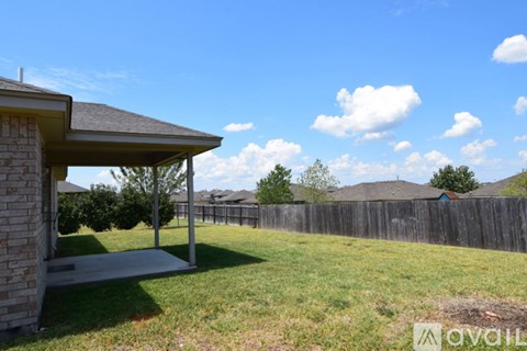 A backyard with a wooden fence and a covered patio area.