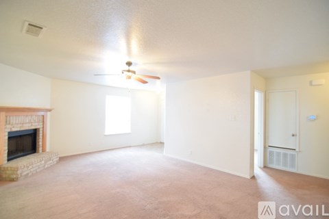 A living room with a fireplace and a ceiling fan.