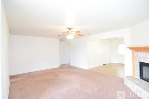 A living room with a fireplace and a ceiling fan.