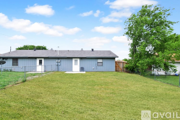 A house with a blue roof and a white door is surrounded by a green lawn.