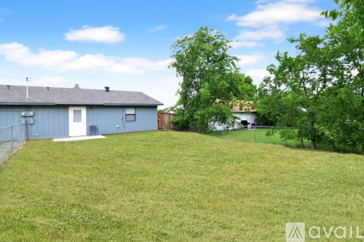 A backyard with a fence and a house in the background.