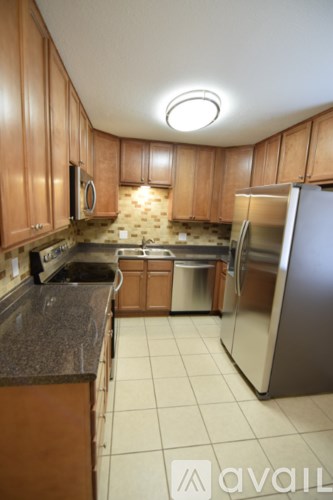 A kitchen with wooden cabinets and a stainless steel refrigerator.