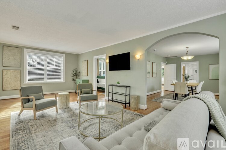 A living room with a grey couch, a glass coffee table, and a television mounted on the wall.
