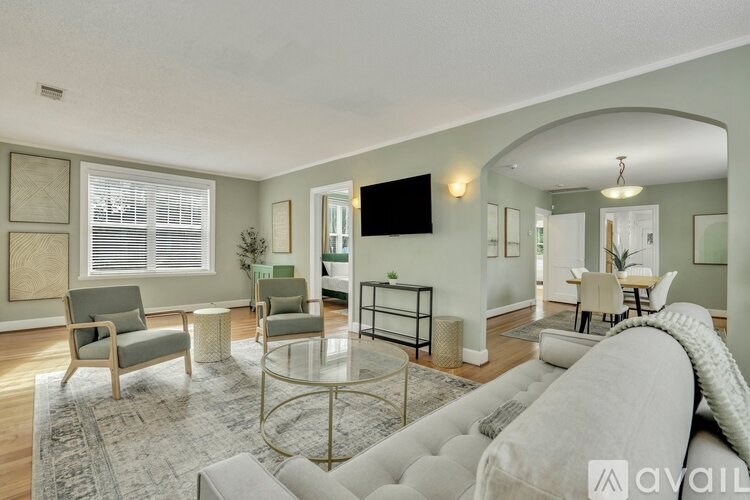 A living room with a grey couch, a glass coffee table, and a television mounted on the wall.