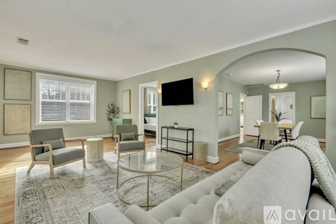 A living room with a grey couch, a glass coffee table, and a television mounted on the wall.