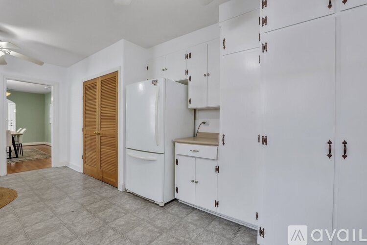 A kitchen with white cabinets and a wooden door.