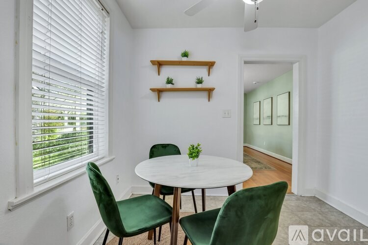 A dining room with a white table and green chairs.