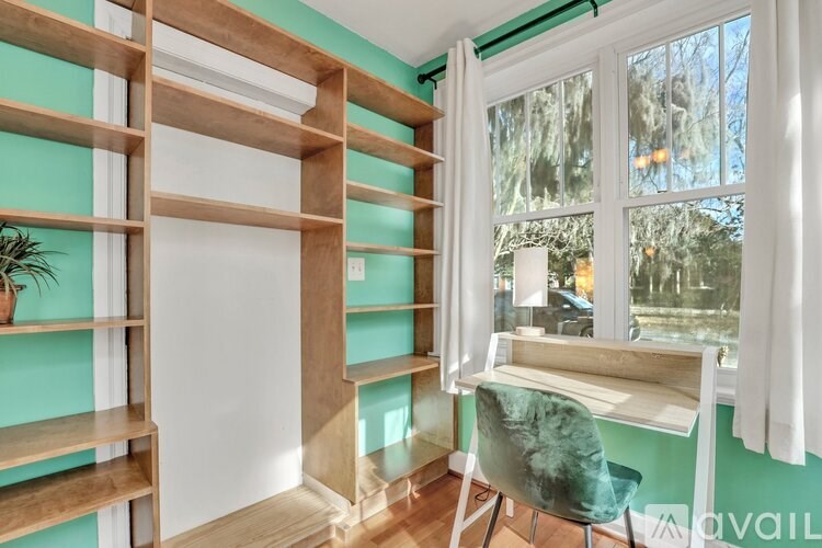 A room with a green chair and a wooden shelf.