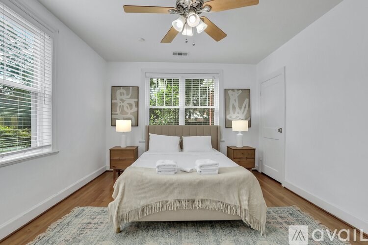 A bedroom with a bed, two lamps, and a ceiling fan.