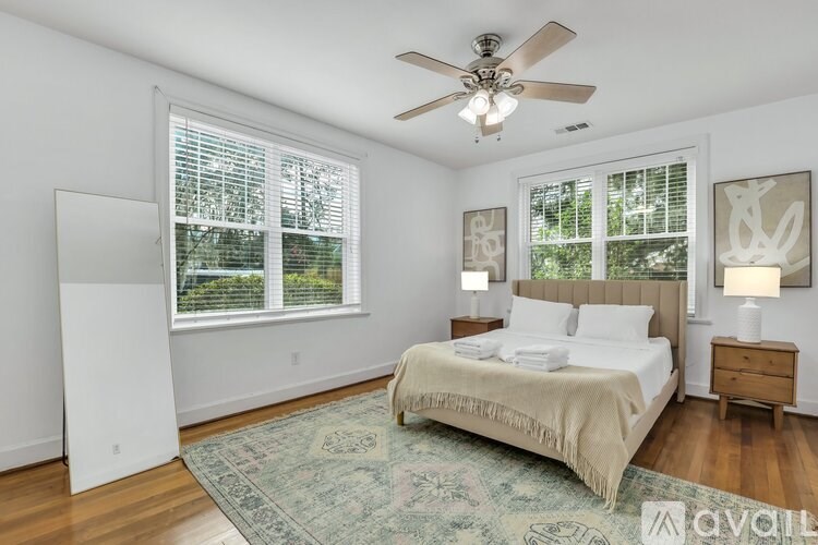 A bedroom with a bed, two lamps, and a rug.