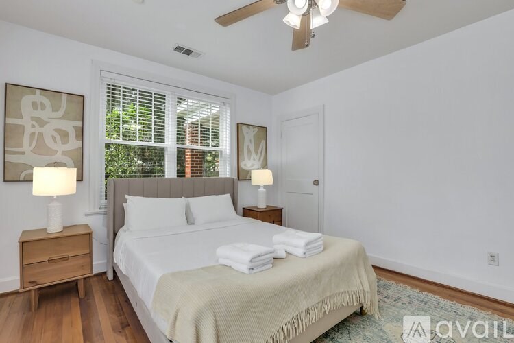 A bedroom with a large bed and a window with blinds.