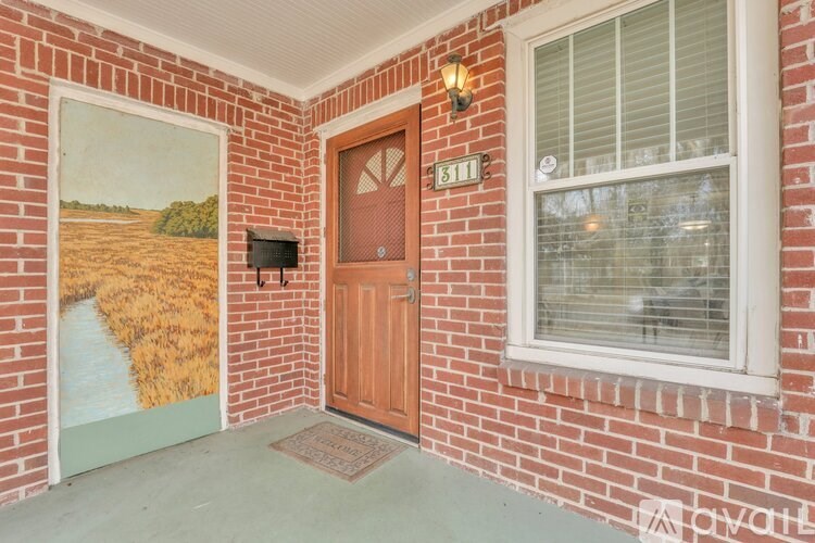 A room with a brown door and a painting of a field on the wall.