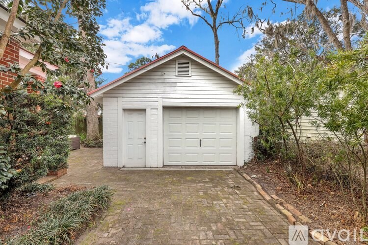 A white garage door is closed and there is a brick pathway leading to it.