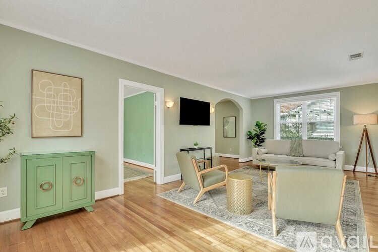 A living room with a green cabinet, a grey couch, and a wooden floor.