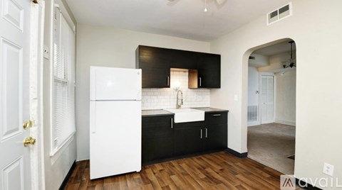 A kitchen with a white refrigerator and black cabinets.