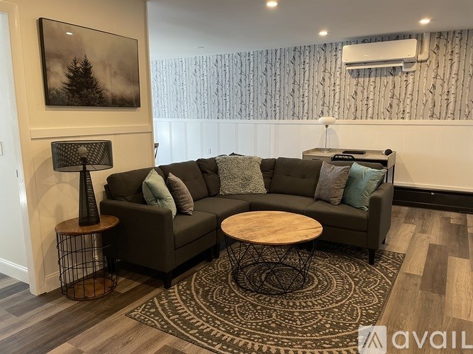 A living room with a grey couch, a wooden table, and a patterned rug.