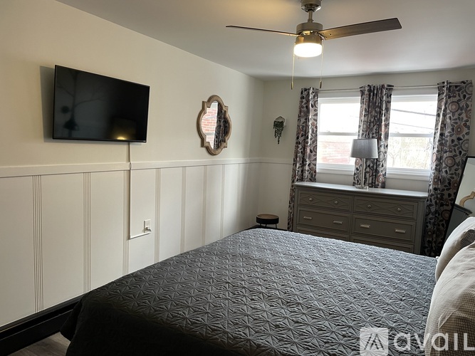 A bedroom with a bed, dresser, and television.