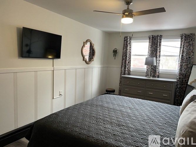 A bedroom with a bed, dresser, and television.