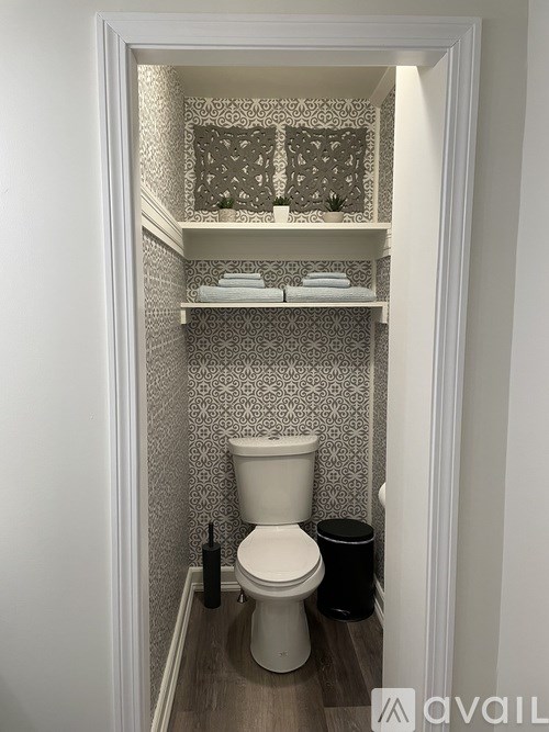 A white toilet in a bathroom with a patterned wallpaper.