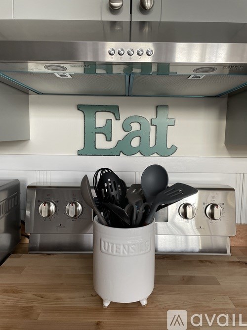 A kitchen with a stove top oven and a utensil holder.