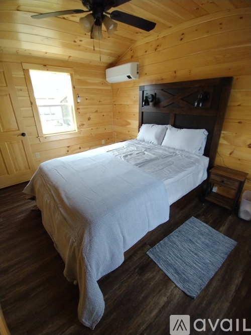 A bedroom with a bed, a ceiling fan, and a window.