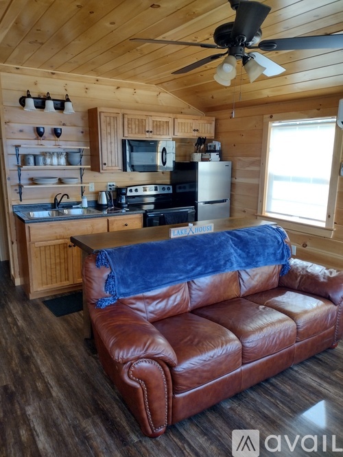 A brown leather couch in a kitchen with wooden cabinets and a ceiling fan.