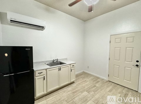 A kitchen with a black fridge, white cabinets, and a white door.