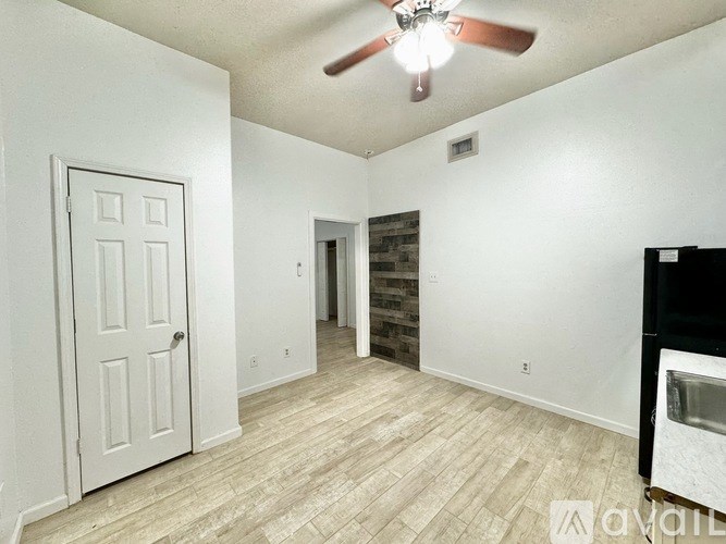 A room with a ceiling fan and a door on the left.
