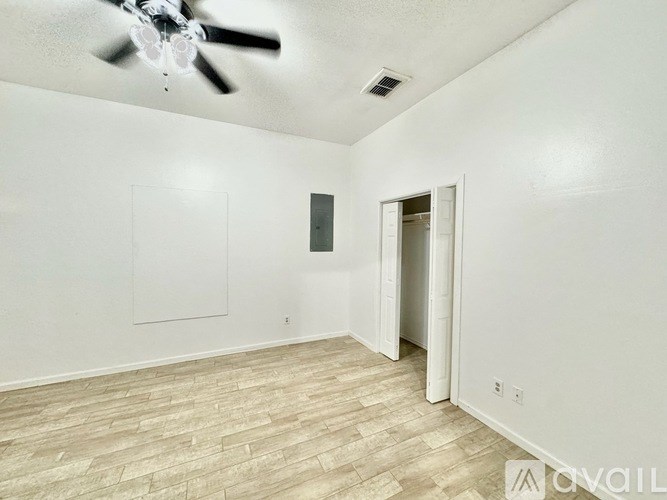 A room with a ceiling fan and a door leading to another room.
