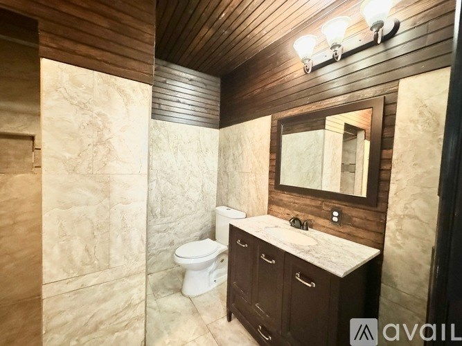 A bathroom with a toilet, sink, and mirror.