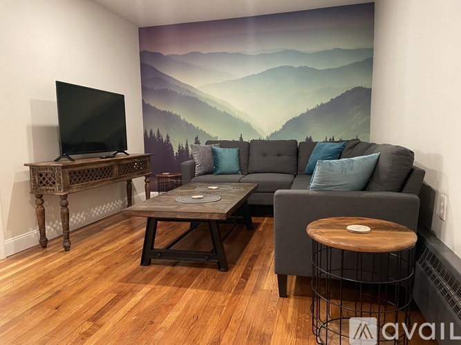 A living room with a grey couch, a wooden coffee table, and a television.