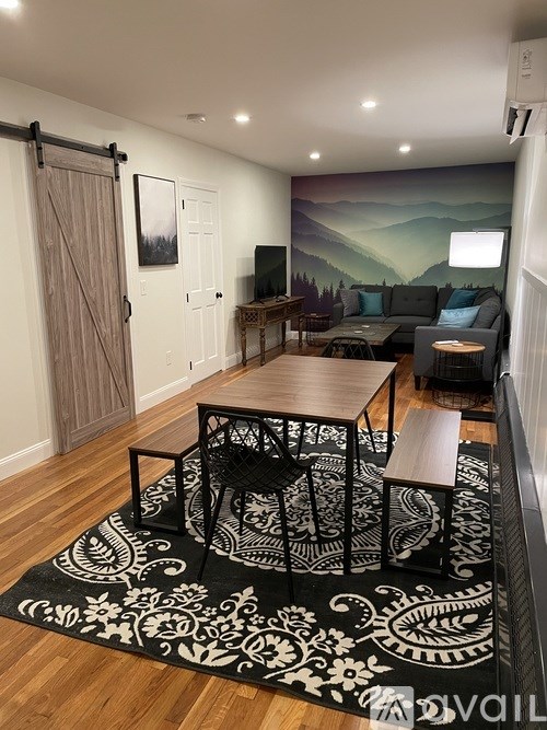 A living room with a black and white rug and a wooden table.