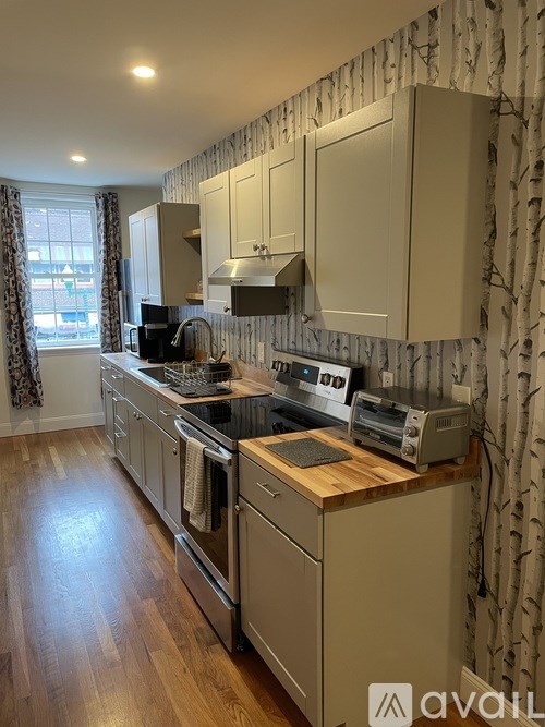 A kitchen with wooden floors and a patterned wallpaper.