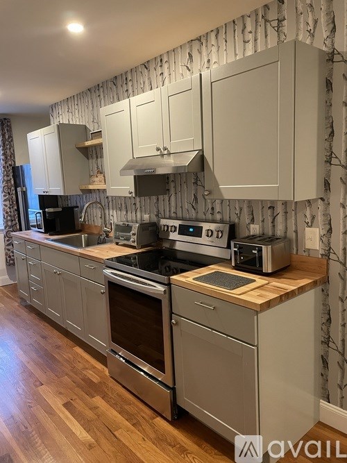 A kitchen with wooden floors and a patterned wallpaper.